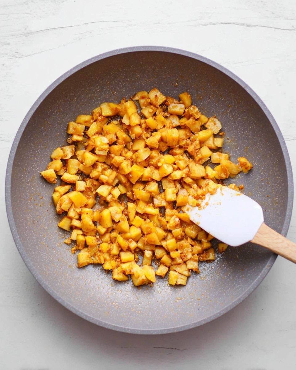 The image shows a spoon full of a golden brown fruit crumble with visible chunks of yellow fruit and oat topping held above a white plate with a swirl of white whipped cream on a white marbled surface. The crumble in the spoon appears crunchy with textured oats and small bits of browned nuts or cinnamon. Behind the spoon, there are three white bowls filled with the same crumble, sitting on a white marbled surface with a blue and white checkered cloth nearby and a white and yellow striped cloth. Photo taken with an iphone --ar 4:5 --v 7