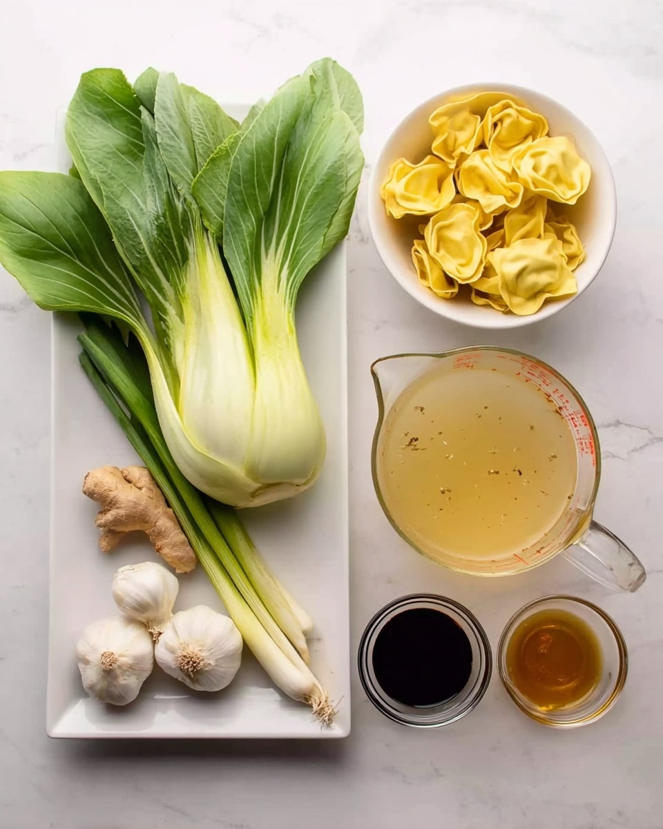 The image shows various fresh ingredients arranged neatly on a white marbled surface. On the left, there is a white rectangular plate holding a fresh pale green bok choy with broad leaves, two white garlic cloves, a small piece of light brown ginger, and three long white and green scallions. To the right of the plate, there is a small white bowl filled with several yellow tortellini pasta pieces. Next to the bowl is a clear glass measuring jug containing a light golden broth with tiny floating bits. In front of the jug, three small clear glass bowls hold a small amount of clear liquid, dark soy sauce, and amber-colored oil, lined up in a row. The image is bright with a clean and fresh look, emphasizing natural colors and textures. Photo taken with an iphone --ar 4:5 --v 7