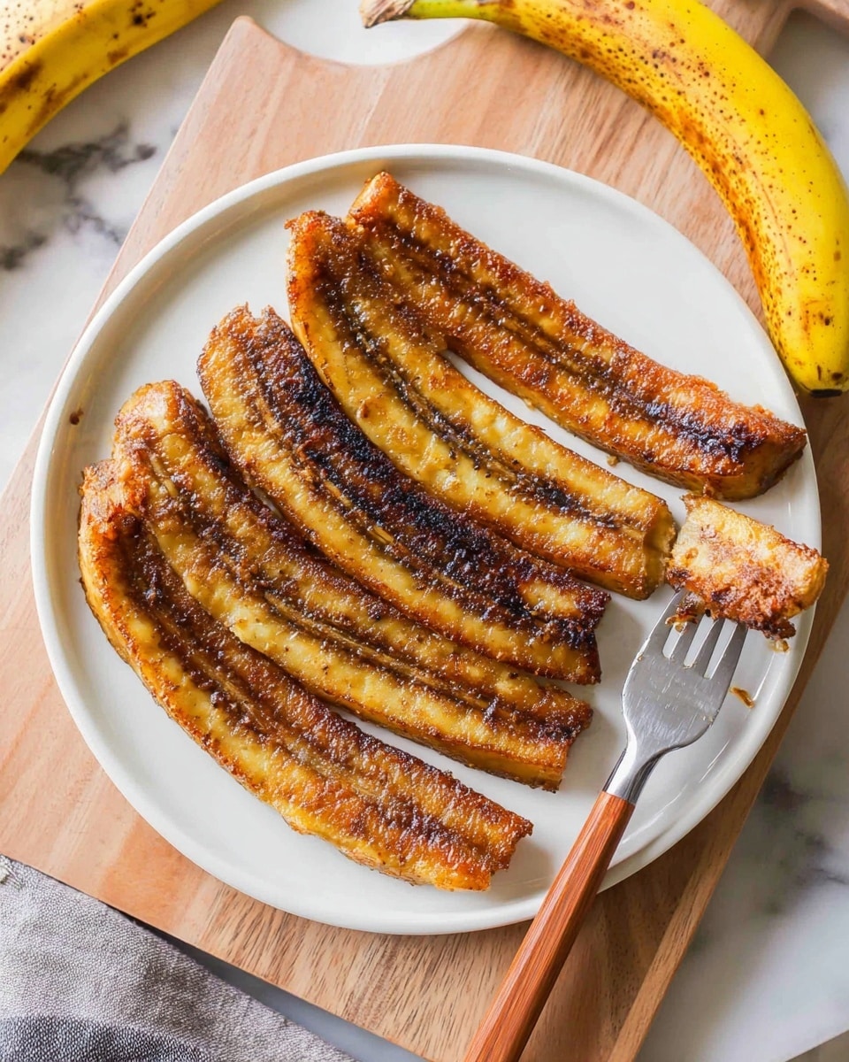 A white plate holds four long, thin slices of golden brown cooked plantain arranged in a fan shape. On top of the plantains is a soft, white scoop of whipped cream sprinkled with light brown cinnamon powder. A silver fork with a wooden handle rests to the right side on the plate, which sits on a light wooden board. The background shows a white marbled surface with blurred objects. photo taken with an iphone --ar 4:5 --v 7