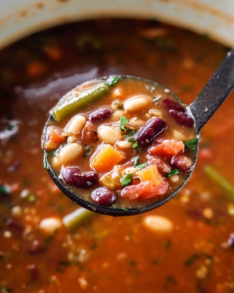A white bowl filled with a bright red tomato soup containing visible layers of white beans, red kidney beans, macaroni pasta, sliced orange carrots, green beans, and small chunks of tomato. On top, there is a generous layer of grated pale yellow cheese sprinkled with fresh green parsley. The spoon inside the bowl adds a vertical silver element to the composition. The bowl rests on a dark wooden table with a white knotted cloth visible in the background. photo taken with an iphone --ar 4:5 --v 7