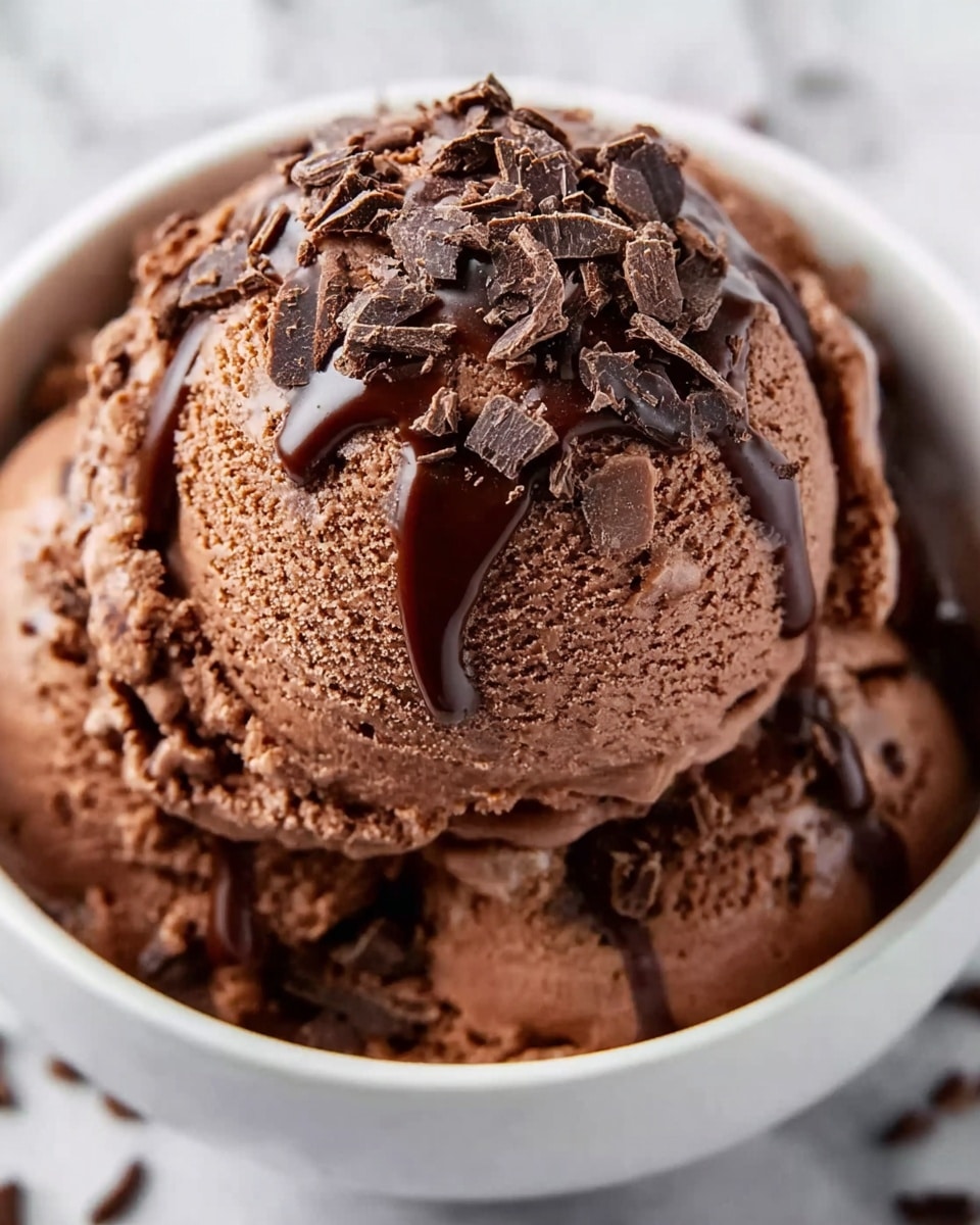 A shiny metal pot filled with smooth, glossy melted chocolate that has a rich, dark brown color and creamy texture. A light wood spoon rests inside the pot, partially coated with the chocolate, showing thick swirling patterns on the chocolate surface. The pot sits on a white marbled surface with soft natural light highlighting the chocolate’s shiny surface. Photo taken with an iphone --ar 4:5 --v 7