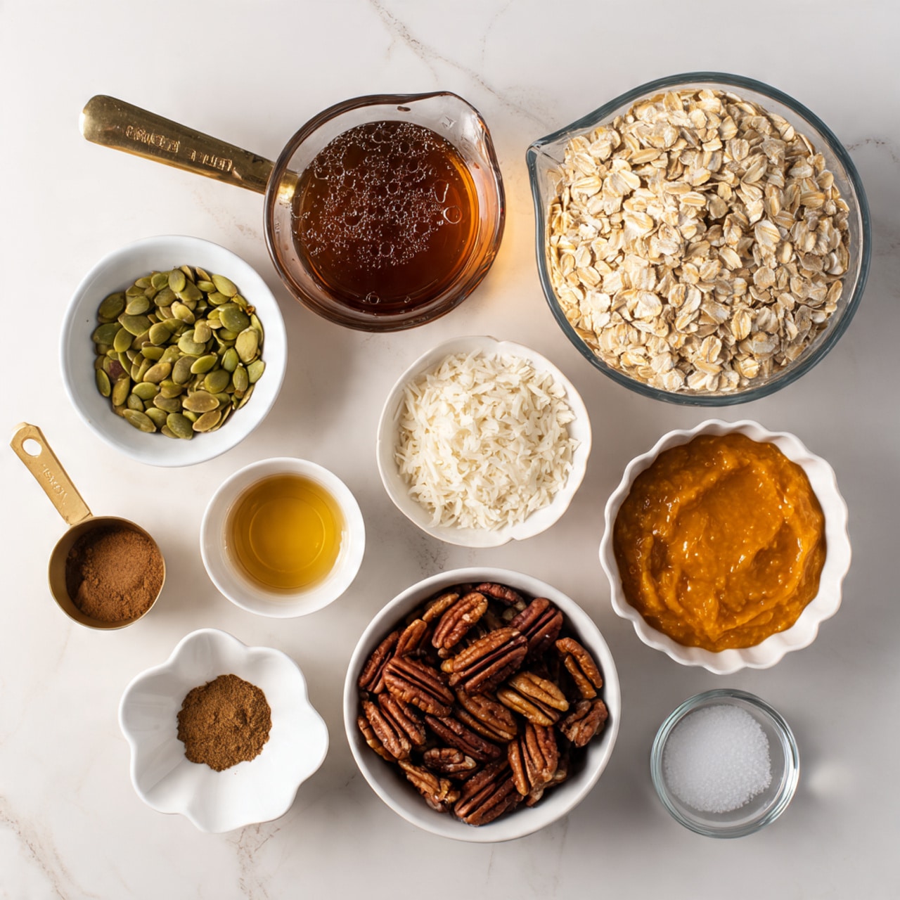 The image shows several layers of ingredients placed separately on a white marbled surface. There is a large clear measuring cup filled with light beige rolled oats at the top right. To the left, a smaller clear measuring cup holds dark amber maple syrup with bubbles on the surface. Below the oats, a white bowl contains small white shredded coconut flakes, while next to it on the left, another white bowl is filled with green pumpkin seeds. Nearby, a small white bowl holds brown ground cinnamon, and beside it, a small white bowl has darker brown ground nutmeg. A brass measuring cup contains smooth, orange pumpkin puree in the middle left. Below, a white bowl is filled with dark brown pecan halves. On the lower left side, a small white scalloped bowl holds a golden liquid, likely vanilla extract. Next to it, a small dark bowl contains white salt. At the bottom right, there is an empty clear measuring cup. All ingredients are neatly arranged with good spacing, and the photo is taken with an iphone --ar 4:5 --v 7