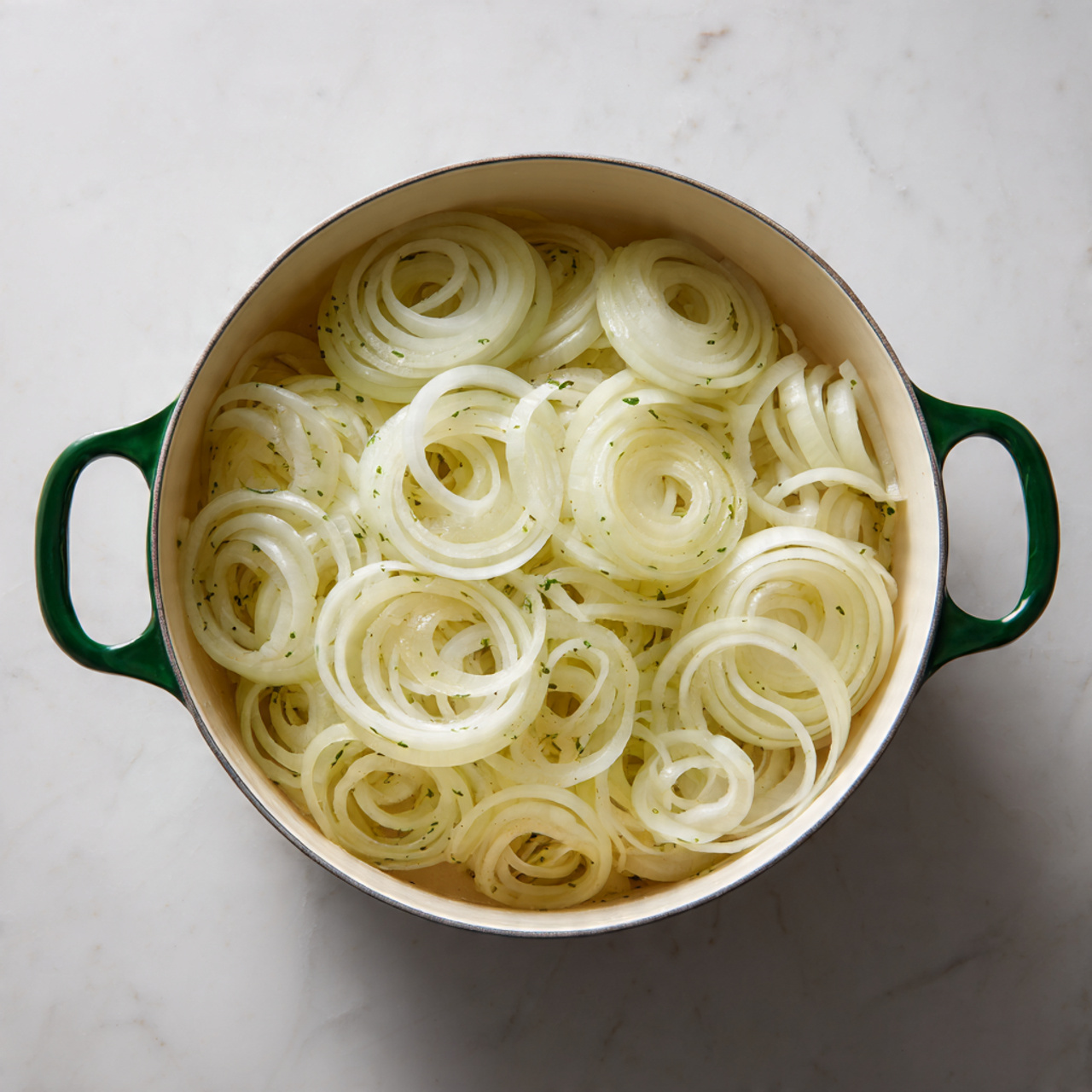 The image shows a deep white pot filled with many layers of thin onion rings. The rings are pale white and light yellow, overlapping each other and covering the entire bottom of the pot. The pot is placed on a white marbled surface, and its green handles are clearly visible on both sides. Photo taken with an iphone --ar 4:5 --v 7