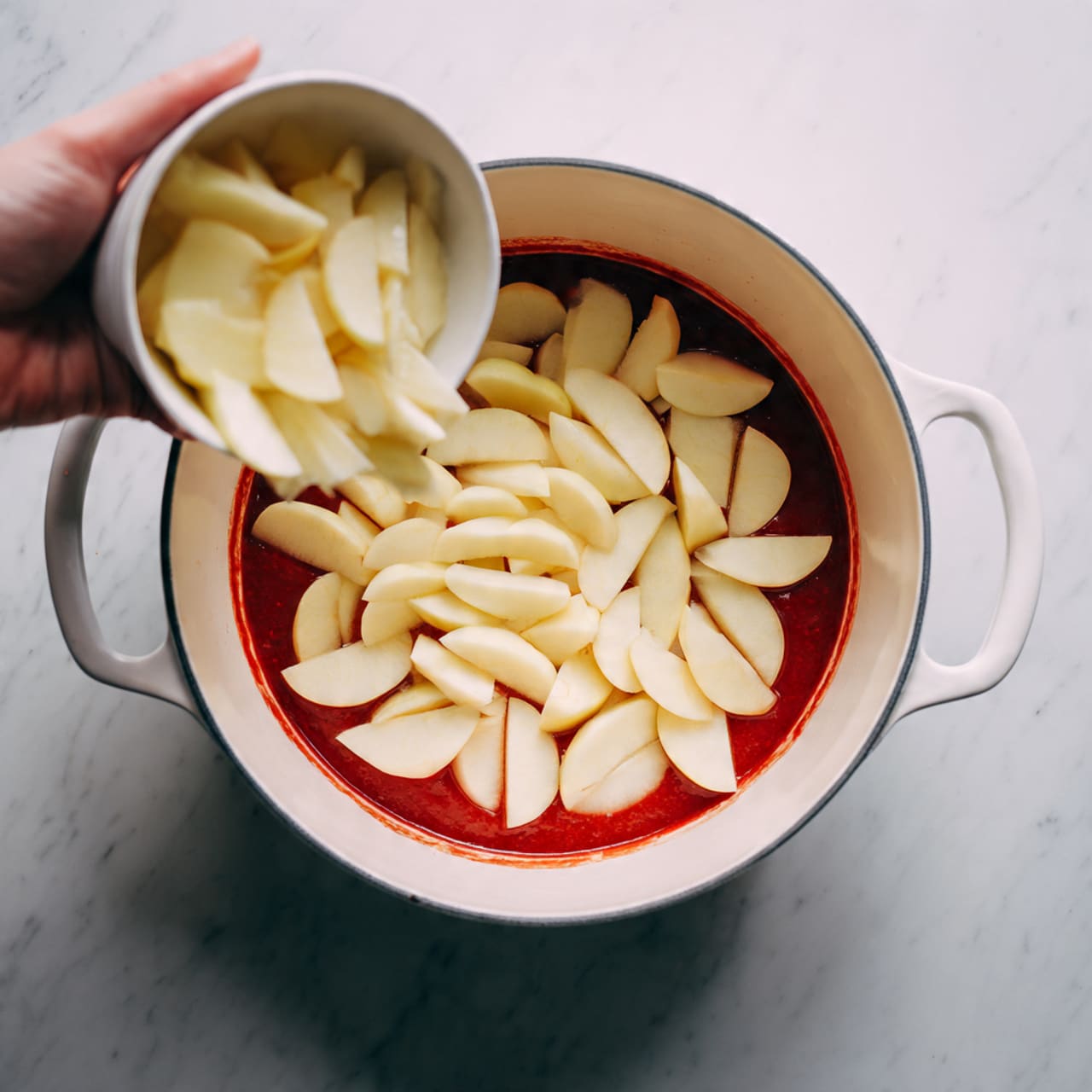A large white pie with a crumbly brown topping that looks crunchy and uneven, covering a thick layer of soft, light golden-brown cooked apple slices underneath. One slice has been removed from the pie, showing juicy, cinnamon-spiced apple filling with sauce spread on the white marbled surface beneath. Nearby are two white plates on the same white marbled surface; one holds a whole slice with the crumbly topping and juicy apple filling, and the other shows a partially eaten slice with some apples and crumbs beside it. photo taken with an iphone --ar 4:5 --v 7