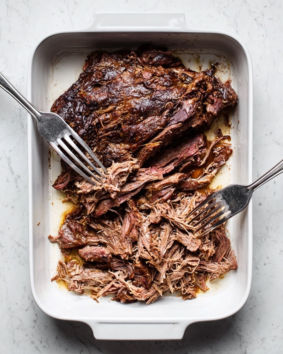 A white baking dish on a white marbled surface holds a large piece of cooked meat being shredded by two metal forks. The meat has a dark brown outer layer with a slightly crispy texture, and inside, it shows a tender, light brown color with visible fibers pulling apart in long strips. One fork is pressing down while the other is pulling the meat apart, revealing the soft inside and the contrast between the charred surface and the juicy center. Photo taken with an iphone --ar 4:5 --v 7