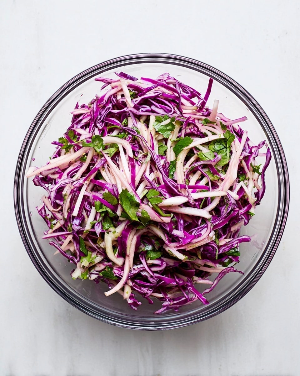 A white plate filled with a fresh salad made of several layers: thinly sliced purple cabbage forming the base, topped with thin sticks of pale green apple, thin strips of red onion, and scattered green fresh mint leaves and cilantro. The salad has a colorful and textured look with varying shades of purple, green, and white. The plate is placed on a white marbled surface next to a small white bowl containing coarse salt and cracked black pepper, three forks with wooden handles, and parts of other plates visible around. photo taken with an iphone --ar 4:5 --v 7