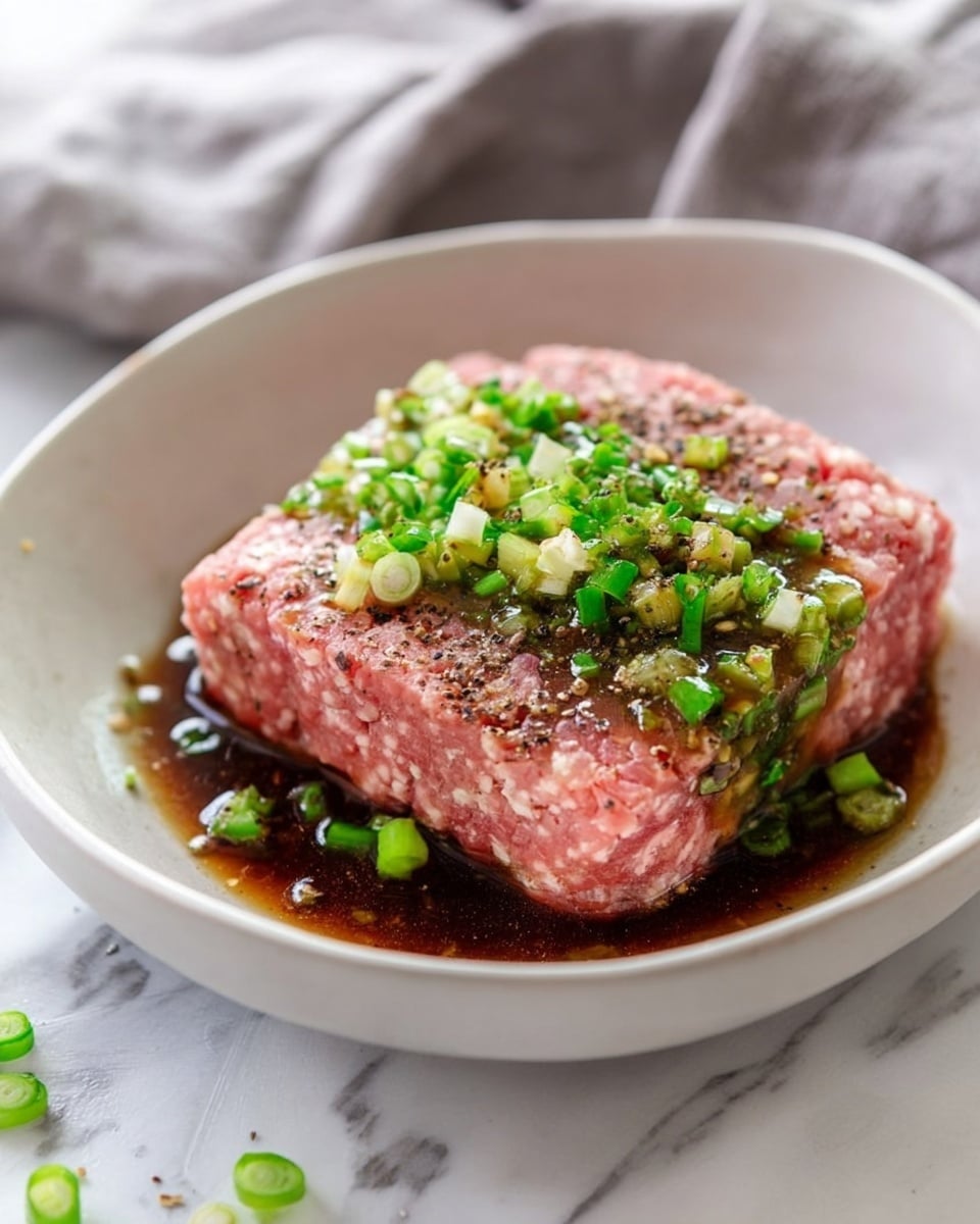 A white bowl filled with round meatballs covered in a thick, shiny dark brown sauce. The meatballs are topped with small white sesame seeds and thin slices of green onions. Around the edges of the bowl, there are orange carrot curls adding a bright color contrast. The bowl sits on a white marbled surface with a soft white and blue striped cloth partially visible next to it. photo taken with an iphone --ar 4:5 --v 7