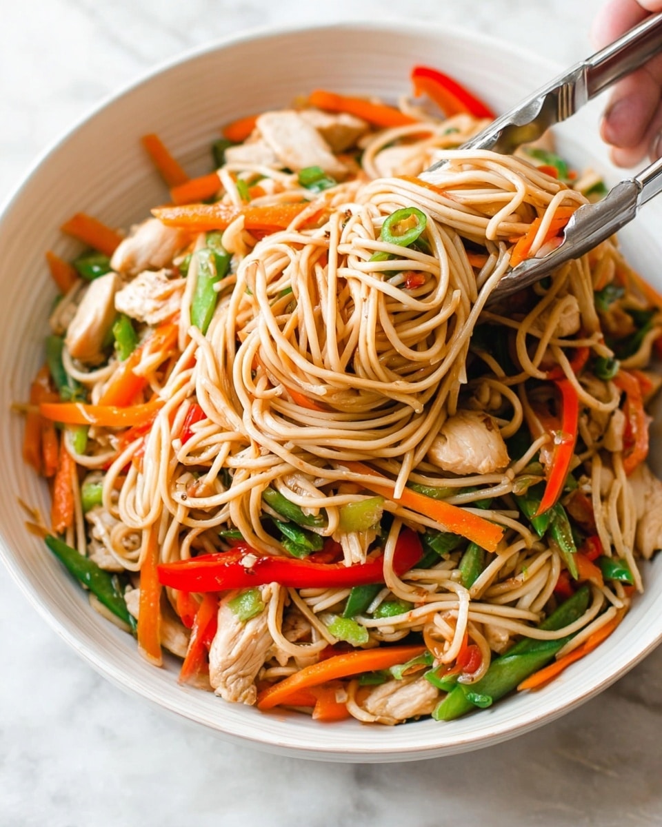 The image shows a white round plate filled with a pile of light brown noodles mixed with thin slices of bright orange carrot, red bell pepper strips, and green vegetables. A woman's hand lifts a bunch of noodles with vegetables high above the plate, creating a vertical flow of strands stretching up from the pile. The background and surface are plain white with a marbled texture, giving a clean and simple look. photo taken with an iphone --ar 4:5 --v 7