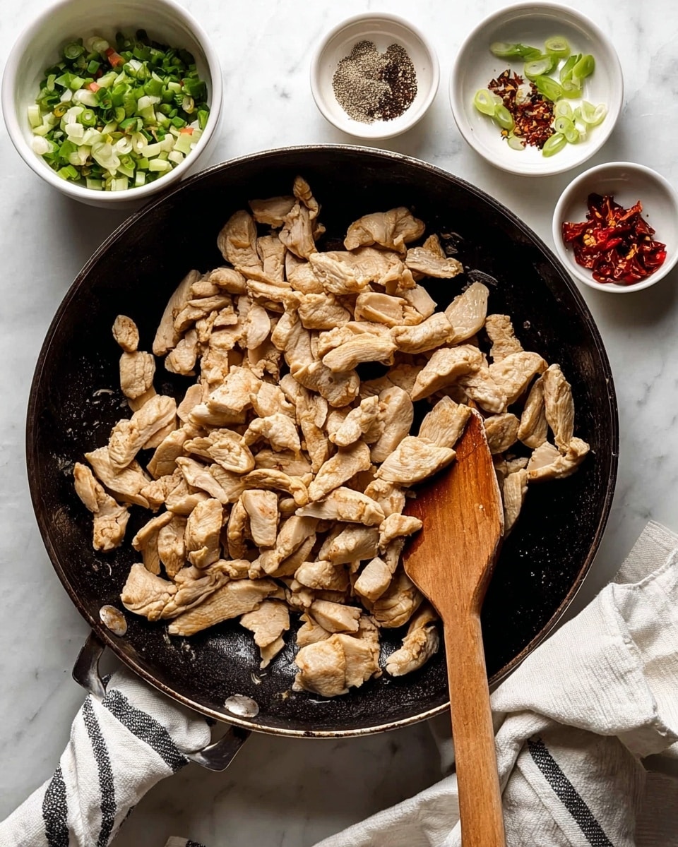 In the center, there is a black pan filled with many pieces of cooked light brown sliced chicken with slight golden edges, showing a tender texture. A wooden spatula rests on the right edge of the pan, slightly mixing the chicken. Around the pan, there are four small white bowls placed on a white marbled surface: one bowl contains a colorful mix of chopped green scallions, another has small pieces of dried red chili, one holds a small pile of black pepper, and the last white bowl is empty. A white cloth with dark thin stripes is folded under the pan handle on the bottom left. photo taken with an iphone --ar 4:5 --v 7