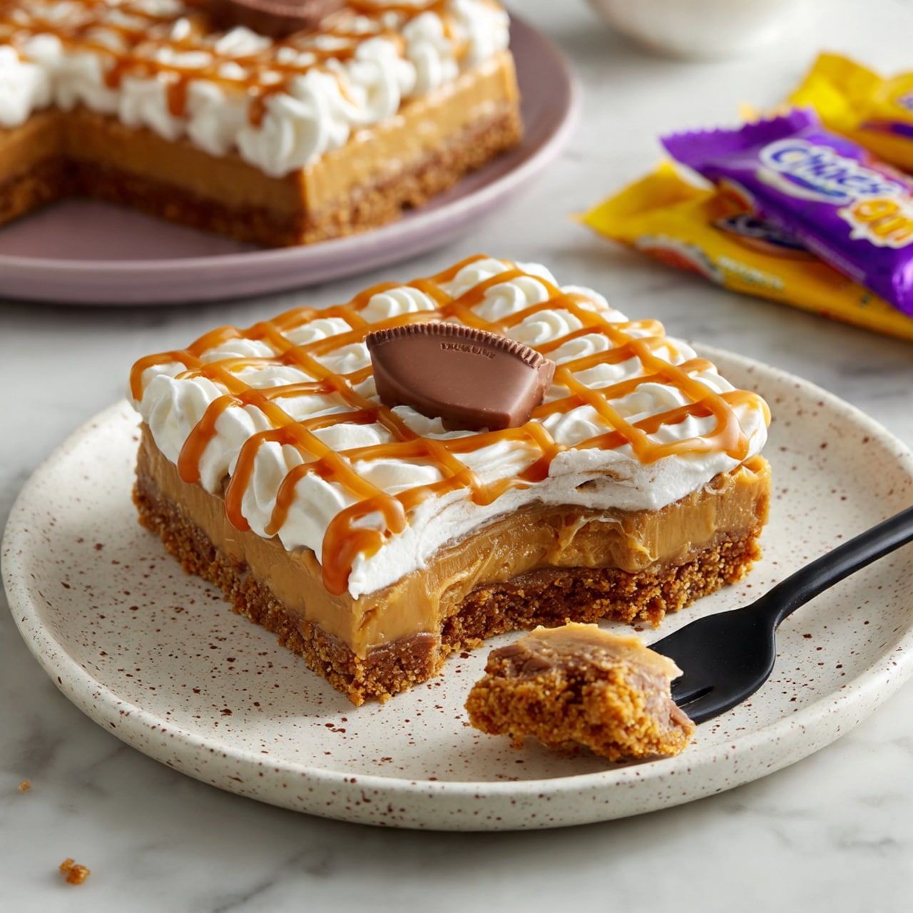 A round layered cake with a light brown base layer and a smooth caramel-colored middle layer on a dark gray round board. The cake is decorated on top with white swirls of cream around the edge, each topped with a half of a caramel-filled chocolate egg. Drizzles of caramel sauce cover the top in a grid pattern and drip slightly down the sides. The cake sits on a white marbled surface with a geometric patterned white plate and a fork in the front, and a gray cloth in the background. Around the cake, there are colorful wrapped caramel chocolates. Photo taken with an iphone --ar 4:5 --v 7