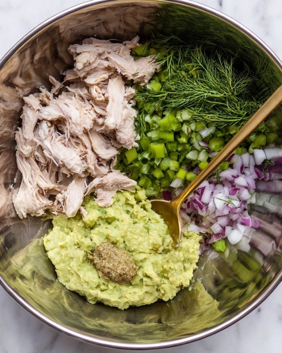 The image shows a white plate with a beaded edge, placed on a white marbled surface, holding three wraps made from bright green lettuce leaves. Each lettuce leaf acts as a base layer, smooth and fresh in texture, topped with a mixture layer that looks chunky and moist, made from light beige shredded chicken, small pieces of red onion, and green herbs. The chicken mixture is positioned neatly in the center of each leaf. A blue and white striped cloth is partly visible under the plate. photo taken with an iphone --ar 4:5 --v 7