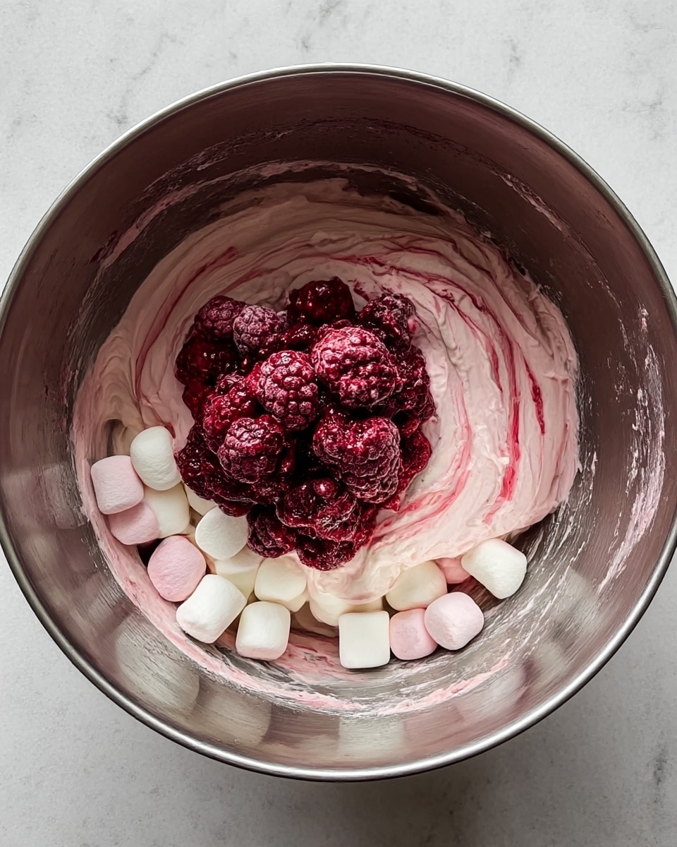 The image shows a clear glass filled with a layered dessert placed on a white marbled surface with a festive cloth underneath. The dessert has multiple layers starting with a pale pink creamy layer mixed with small, soft white pieces at the bottom. Above it is a bright white cream layer topped with sliced fresh red strawberries scattered inside. Another thick layer of light pink creamy mixture with strawberry bits covers these, followed by a topping of whole and sliced strawberries, dollops of white cream, and sprinkled with small shavings of brown chocolate. In the background, two more similar glasses are visible filled with the same layered dessert. Two golden spoons and a green cloth napkin are placed near the glass. photo taken with an iphone --ar 4:5 --v 7