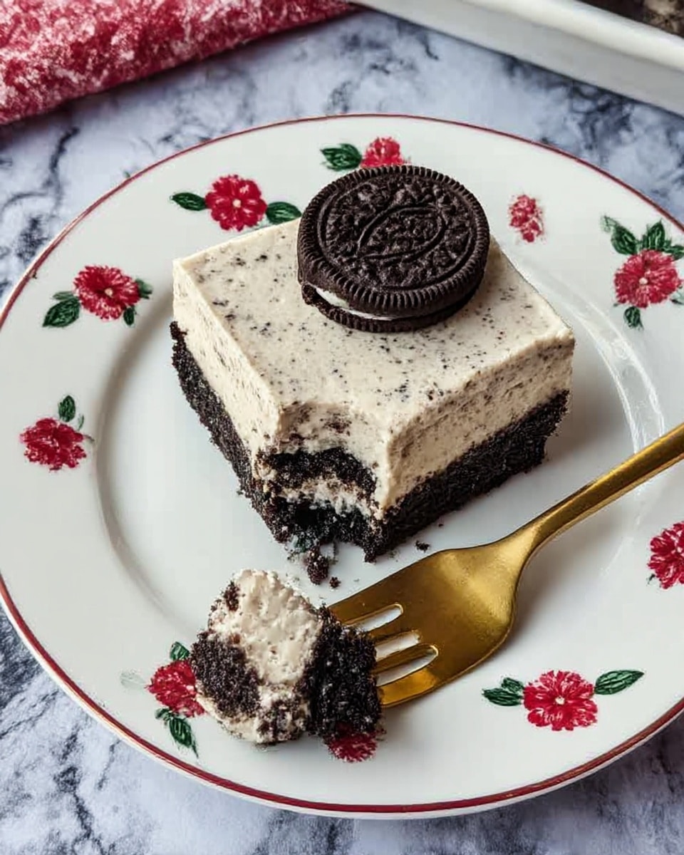 The image shows a white rectangular plate filled with 15 square bars arranged in a 3 by 5 grid. Each bar has two layers: the bottom layer is dark and crumbly, likely made from crushed cookies, and the top layer is thick, creamy, and light beige with visible small dark cookie bits mixed in. On top of each bar, there is a half of a small dark sandwich cookie placed in the center. The plate sits on a white marbled surface with a pink woven cloth partially visible in the background, along with some stacked white plates and golden forks. photo taken with an iphone --ar 4:5 --v 7