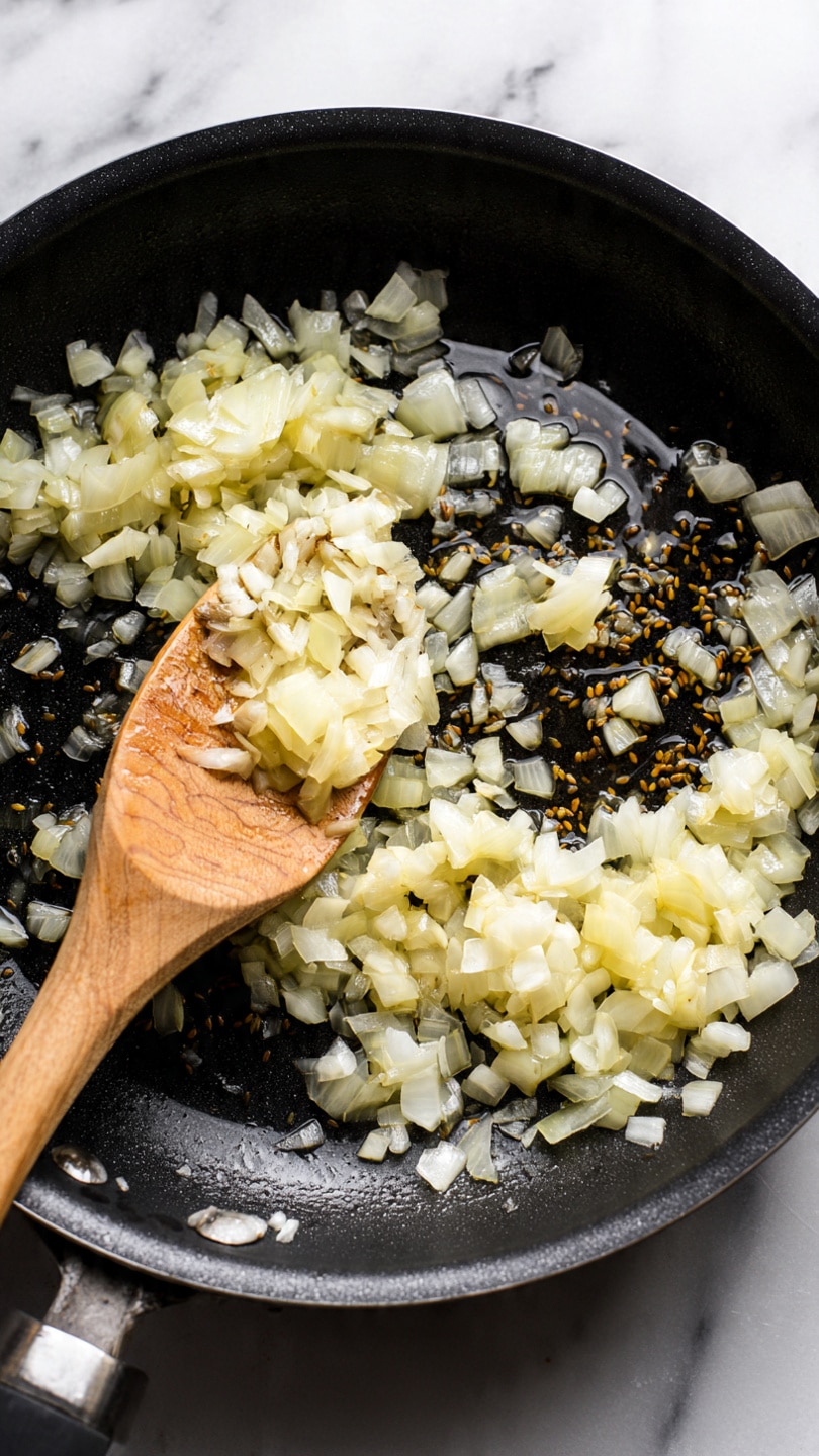 A black frying pan with a white handle is filled with a chunky stew made of light brown sauce mixed with diced orange potatoes and dark purple eggplant pieces, topped with fresh green herbs. The pan sits on a white marbled surface next to torn pieces of flatbread on a black and white striped cloth, and a white bowl with white sauce is partially visible nearby. The whole scene has a clean, rustic look. photo taken with an iphone --ar 4:5 --v 7