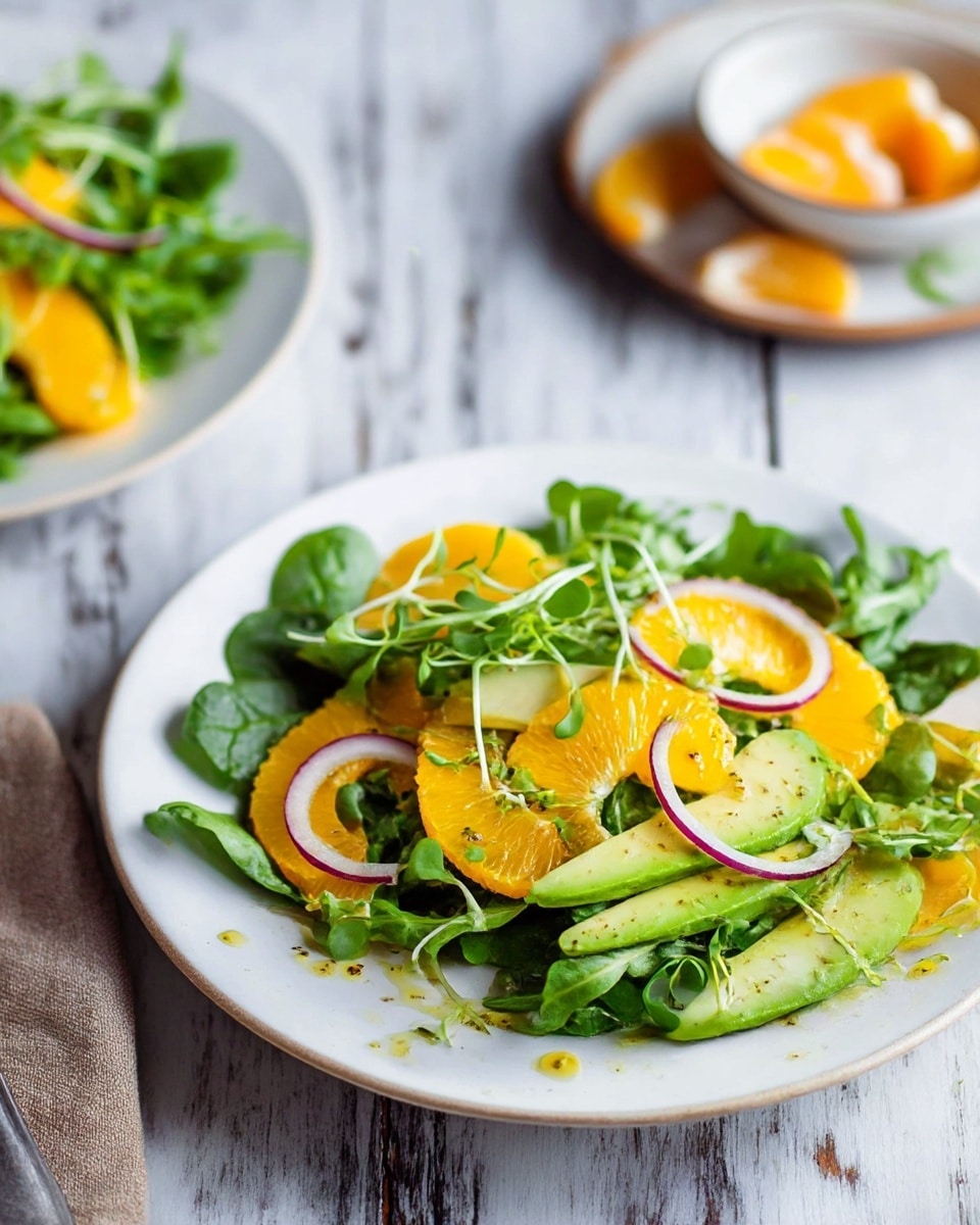 A white plate holds a fresh salad with three main layers: at the bottom, green leafy watercress with small round leaves, topped with bright orange citrus segments that are smooth and juicy, and thin light green slices of avocado with soft texture. Thin slices of purple onion are scattered on top, along with some microgreens with thin green stems and small leaves placed in the center. A vintage brass and dark wood fork rests on the left side of the plate. The plate is set on a rustic wooden surface. Nearby, a small bowl contains pieces of fresh ginger and bright orange turmeric root. photo taken with an iphone --ar 4:5 --v 7