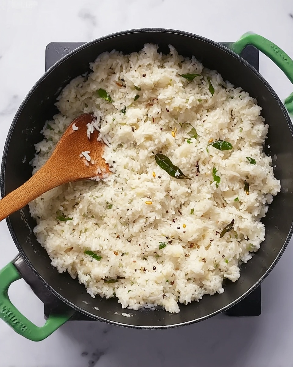 The image shows a black cooking pot filled with a soft, white rice dish that looks fluffy and moist. The rice is mixed with small green leaves and bits of light brown seeds or spices scattered evenly throughout. A wooden spoon rests inside the pot, partly buried in the rice. The pot has green handles, and it is placed on a white marbled surface. photo taken with an iphone --ar 4:5 --v 7