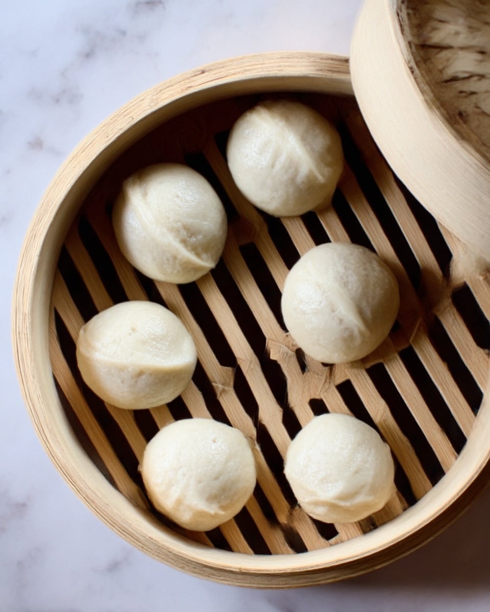 A woman's hand is holding a soft, white steamed bun filled with colorful layers. The lower layer has green lettuce and thin slices of red and orange vegetables, topped with thin purple cabbage strips. A creamy white sauce is drizzled on top with small black seeds scattered over it. In the background, more similar buns filled with the same colorful mix sit in a white steamer basket on a white marbled surface. The lighting is natural and soft, highlighting the fresh ingredients and fluffy texture of the buns photo taken with an iphone --ar 4:5 --v 7
