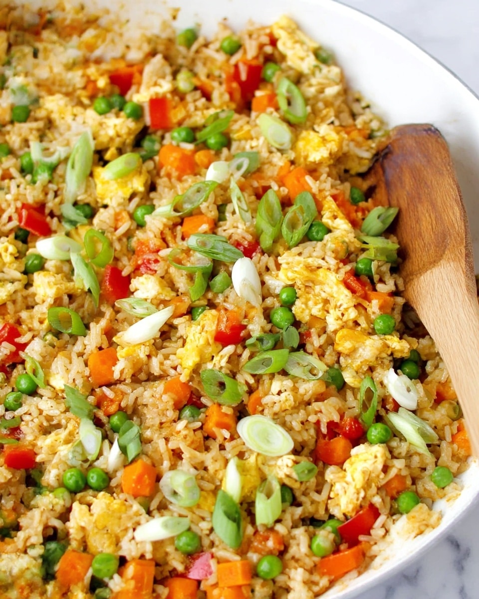 A close-up top view of a white pan filled with fried rice showing three main layers: the base layer of light brown cooked rice mixed with small green peas and diced orange carrots; scattered chunks of yellow scrambled eggs in the middle; and topped with sliced green onions and small pieces of red bell pepper scattered across the top. Two wooden spoons are partially resting inside the pan, one on the left side and the other on the right, with a white marbled surface underneath the pan. photo taken with an iphone --ar 4:5 --v 7