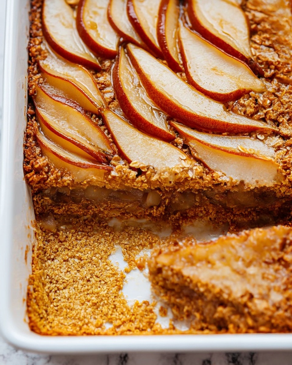 The image shows a baked dish in a white rectangular pan with three visible layers: the bottom layer is a dense, golden oat mixture with a slightly crumbly texture; the middle layer consists of a moist, spiced filling with pieces that look like cooked fruit, light brown and tender; the top layer has thinly sliced pears neatly arranged in overlapping rows, with their reddish-brown skin visible around the edges and a glossy finish that hints at a syrup or glaze. One corner is scooped out, showing the thickness of each layer. The background is a white marbled surface. Photo taken with an iphone --ar 4:5 --v 7