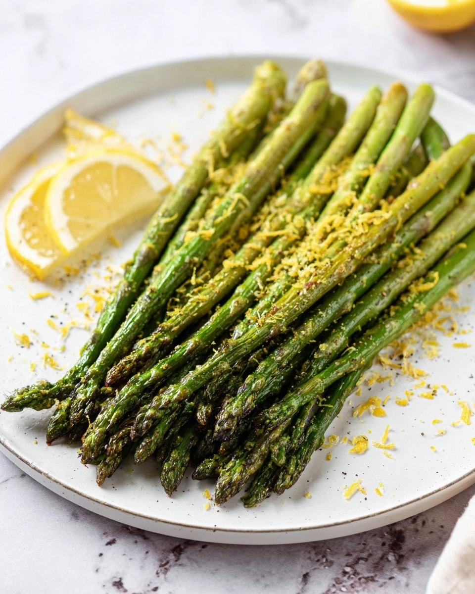 The image shows a white round plate with one layer of grilled green asparagus spears neatly lined up parallel to each other, with slightly charred tips and a tender texture. Bright yellow lemon zest is lightly sprinkled across the asparagus, adding a fresh and colorful contrast. Two lemon wedges are placed on the white marbled surface next to the plate on the left side. The background is softly blurred, making the asparagus the main focus. photo taken with an iphone --ar 4:5 --v 7
