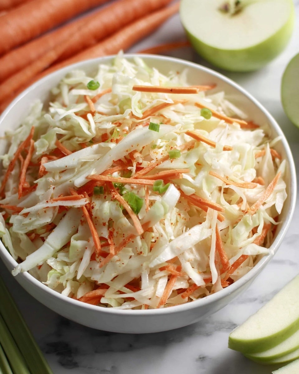 A white bowl filled with a mix of shredded white cabbage and thin orange carrot strips, topped with small pieces of green onion scattered over the top. The bowl sits on a white marbled surface with whole carrots and a sliced green apple partially visible around it. The vegetables have a fresh, crisp texture and the colors are bright and natural. Photo taken with an iphone --ar 4:5 --v 7