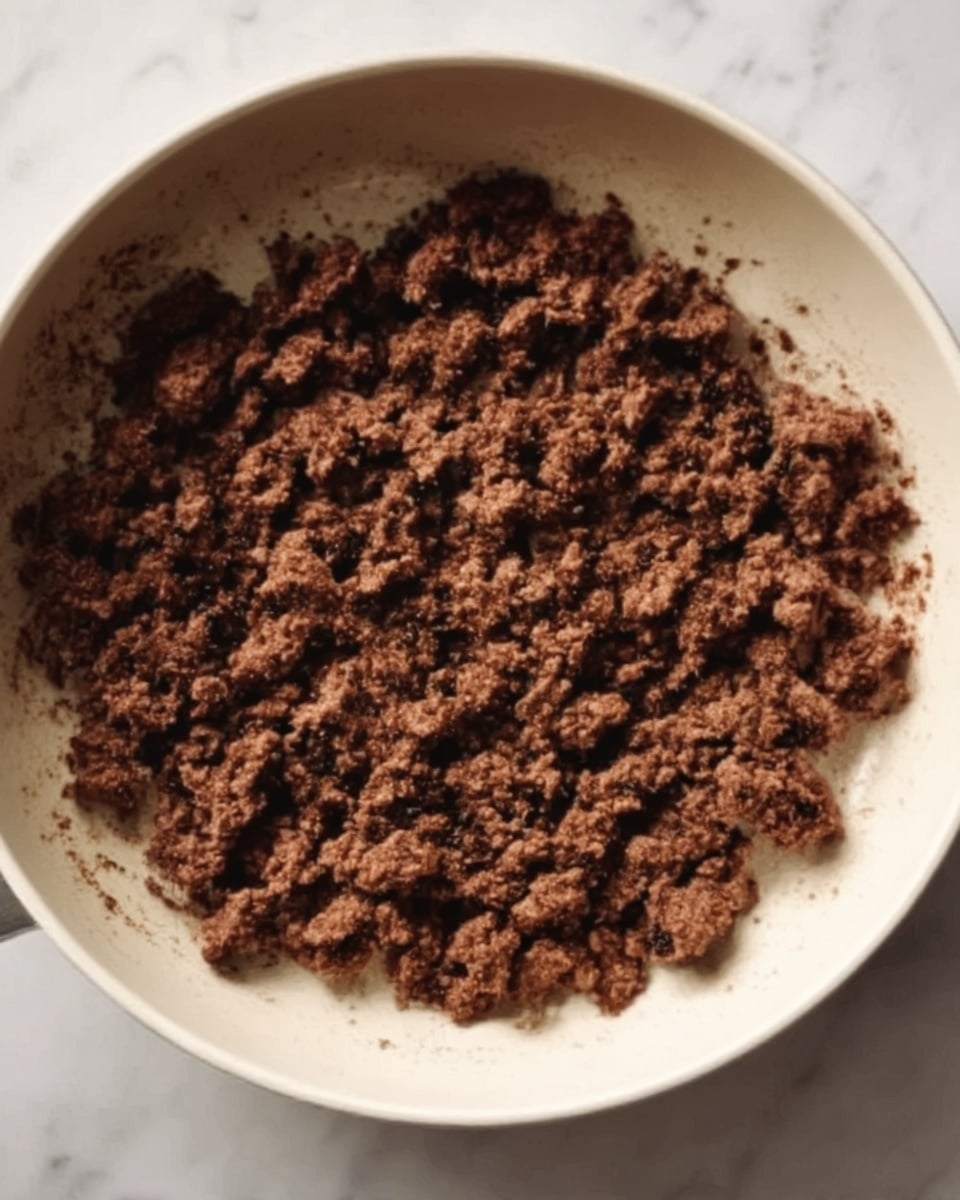 A black oval dish filled with spaghetti covered in a thick, bright red tomato sauce with chunks of tomato and small pieces of meat mixed in, the pasta strands are long and intertwined, sitting on a white marbled surface with a blue and white checkered cloth on the left side photo taken with an iphone --ar 4:5 --v 7