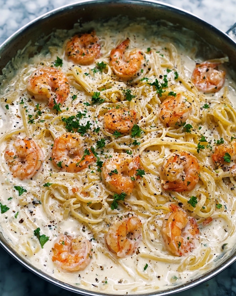 A pan filled with creamy white sauce covering a bed of thin spaghetti noodles, with large orange-pink shrimp scattered evenly on top. The shrimp have a slight char and are dotted with small green parsley leaves. The sauce has a smooth, thick texture with specks of black pepper spread throughout. The spaghetti strands are lightly coated with the sauce and curl gently within the pan. The whole dish rests on a white marbled surface. Photo taken with an iphone --ar 4:5 --v 7
