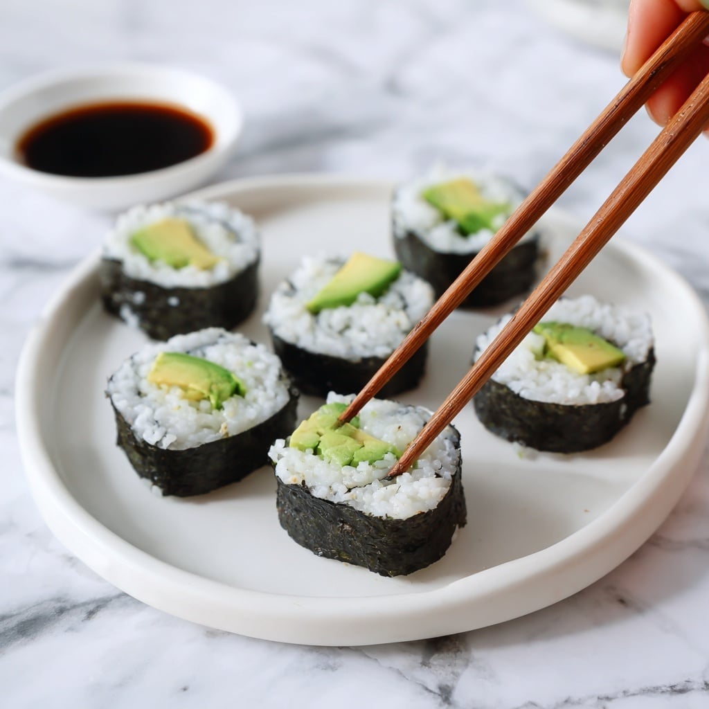 The image shows a flat sushi rolling mat made of thin, light brown bamboo sticks held together with white string, placed on a clear plastic zipper bag with blue and purple lines on the right. On top of the bamboo mat lies a single dark green, shiny, and slightly wrinkled sheet of seaweed (nori), covering most of the mat evenly. The whole scene rests on a white marbled surface. photo taken with an iphone --ar 4:5 --v 7