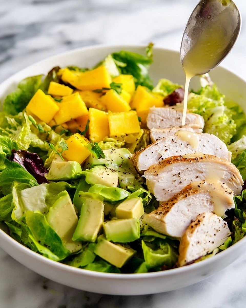 A clear glass bowl filled with a smooth golden-yellow liquid, lightly speckled with small black bits of pepper, sits on a white marbled surface. Next to the bowl is a small silver whisk with a shiny metal handle, with a few drops of the yellow liquid visible on the marble around it. The overall setting is clean and bright, highlighting the fresh sauce inside the bowl. Photo taken with an iphone --ar 4:5 --v 7