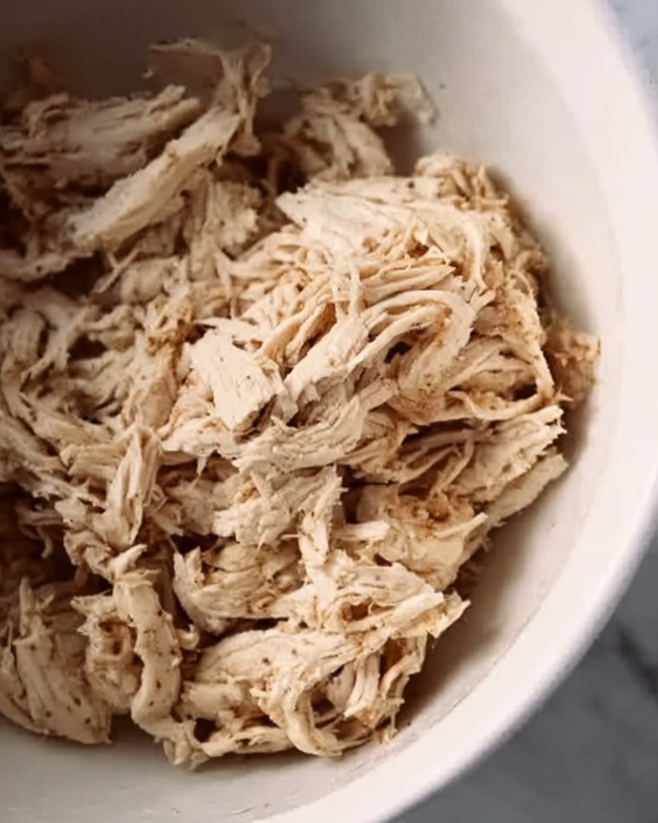 The image shows a white plate with seven golden-brown latkes arranged in a curved line along the edge. The latkes have a crispy texture with visible shredded potato strands and are topped with small, scattered pieces of bright green scallions. On the right side of the plate, there is a small white bowl filled with smooth, pale yellow applesauce. The plate sits on a white marbled surface. photo taken with an iphone --ar 4:5 --v 7