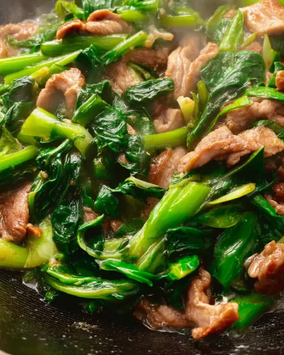 The image shows a black pan filled with a stir fry dish containing several layers. The bottom layer is made of tender brown beef slices scattered evenly throughout the pan. The beef is mixed with a layer of bright green leafy vegetables and stalks, giving a fresh and vibrant look. Small bits of chopped garlic are sprinkled across the dish, adding texture and color contrast. A wooden spoon with a smooth surface rests inside the pan on the left side, partially covered by the food. The background and surface are a white marbled texture. Photo taken with an iphone --ar 4:5 --v 7