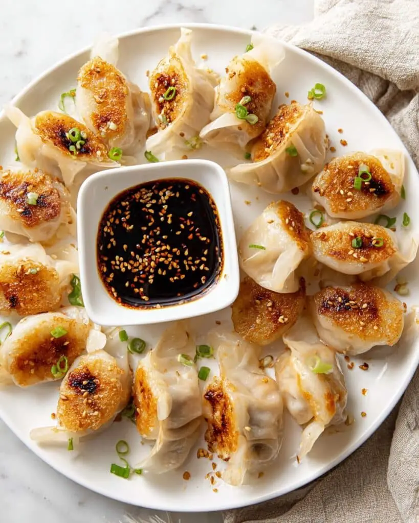 Crispy Pan-Fried Potstickers with Chili Crisp, Green Onions, and Sesame Seeds Recipe
