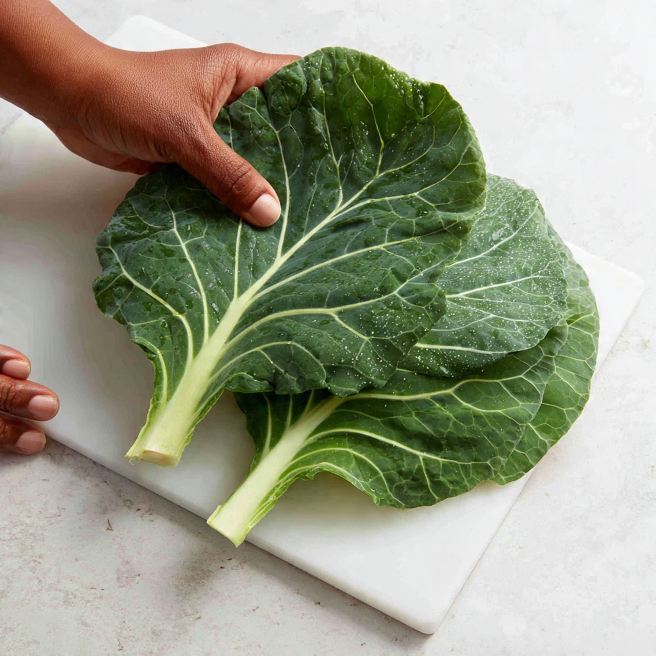 A close-up image of cooked dark green leafy collard greens with small pieces of reddish-brown meat mixed in, all inside a white pot with a dark rim. The greens appear soft and juicy with some broth visible on the right side. A wooden spoon with a textured, twisted handle is partially dipped into the greens inside the pot. The pot is placed on a white marbled surface. photo taken with an iphone --ar 4:5 --v 7