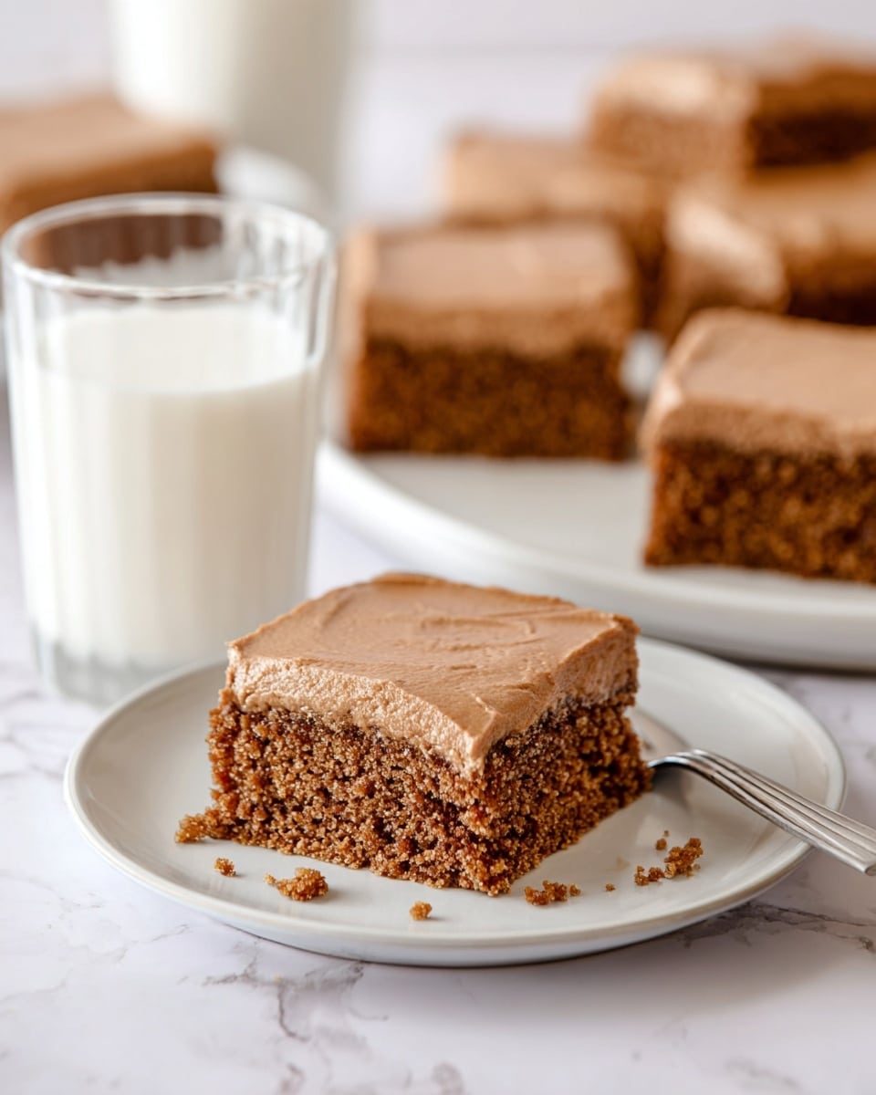 A large white plate in the center holds six square pieces of cake with a light brown, smooth frosting on top, each cake slice having a moist, darker brown base. To the top right, a smaller white plate holds one more square piece of the same cake. At the bottom right, two other white plates each have one square piece of cake with a fork beside them. A vintage styled knife with a wooden handle and some crumbs is placed on the large white plate near the bottom left edge. To the right of the large plate, two clear glasses of milk are placed on the white marbled surface. The whole scene is bright with a clean, simple style. photo taken with an iphone --ar 4:5 --v 7