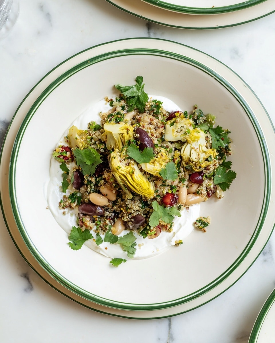 A white bowl with a green rim holds a mixed salad laid over a smooth, thick white cream spread evenly on the bottom right side. The salad consists of three main layers: a base of light green quinoa grains mixed with small white beans, scattered dark purple olives, and artichoke pieces in pale yellow and light green shades, all topped with fresh cilantro leaves in bright green. The bowl rests on a white marbled surface. photo taken with an iphone --ar 4:5 --v 7