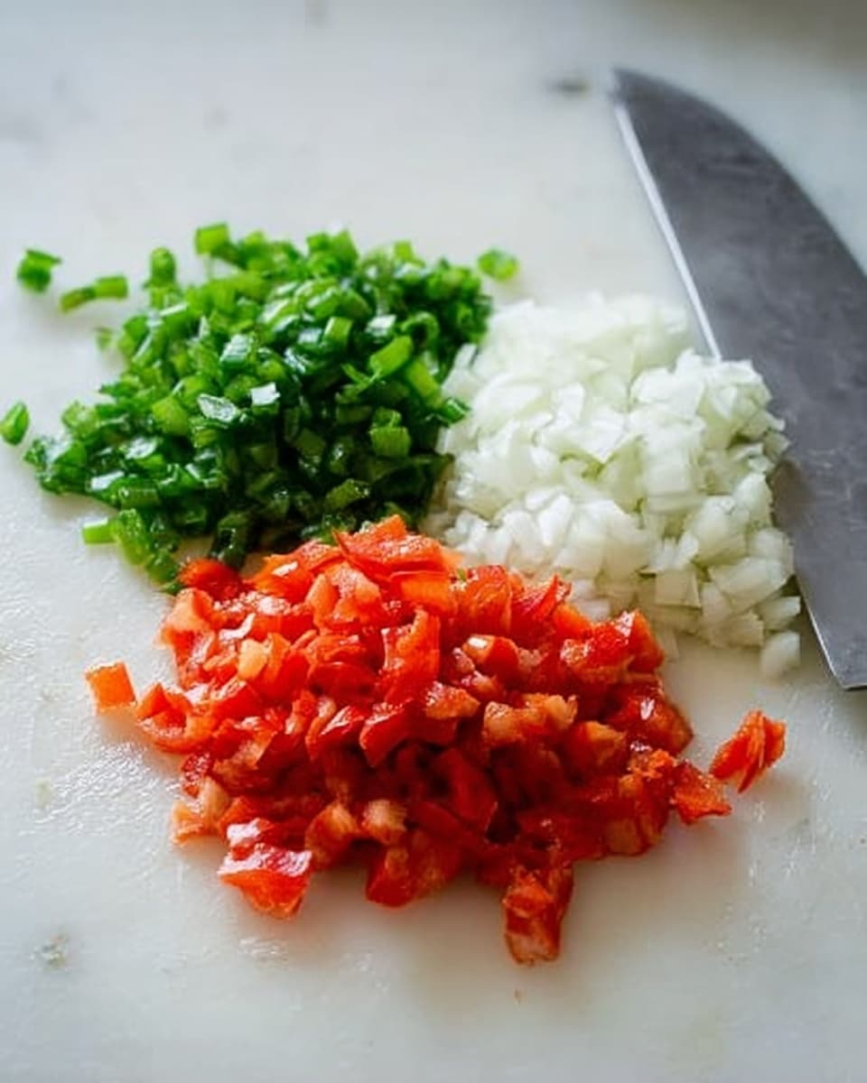 The image shows three piles of chopped vegetables on a white marbled surface. At the front, there is a pile of small red pieces with a juicy texture. Behind it, there is a pile of finely chopped white pieces that look smooth and moist. At the back, there is a pile of small bright green pieces with a fresh, leafy texture. A knife with a silver blade lies on the right side near the piles. The colors are bright, and the white marbled surface makes the vegetables stand out clearly. photo taken with an iphone --ar 4:5 --v 7