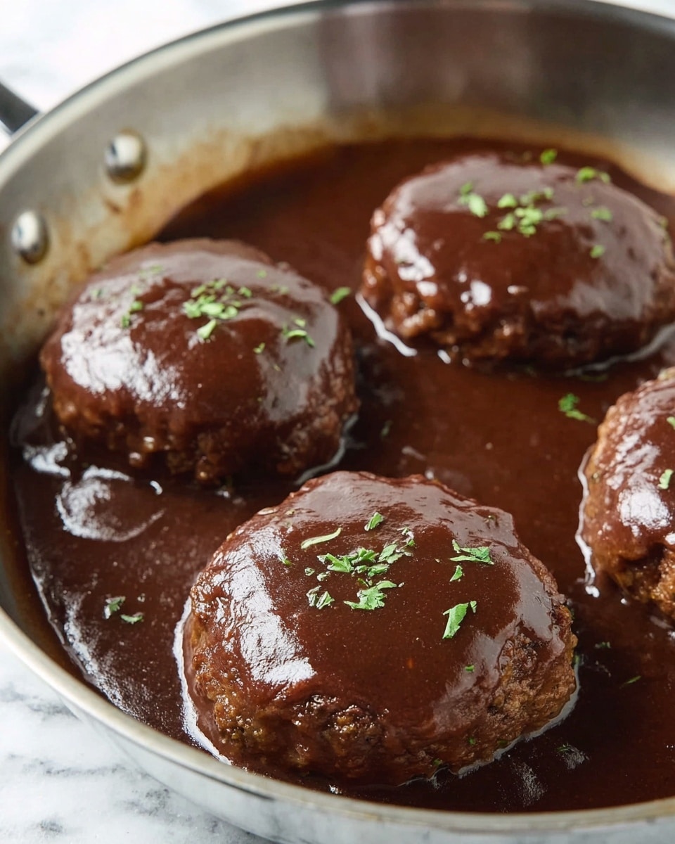 Inside a silver pan, there are four thick round brown patties covered with a shiny dark brown sauce. The sauce looks smooth and slightly glossy, pooling around the patties. Some small green herb pieces are sprinkled on top of each patty, adding a touch of color. The pan sits on a white marbled surface. The image is close up and focused on the patties and sauce. photo taken with an iphone --ar 4:5 --v 7