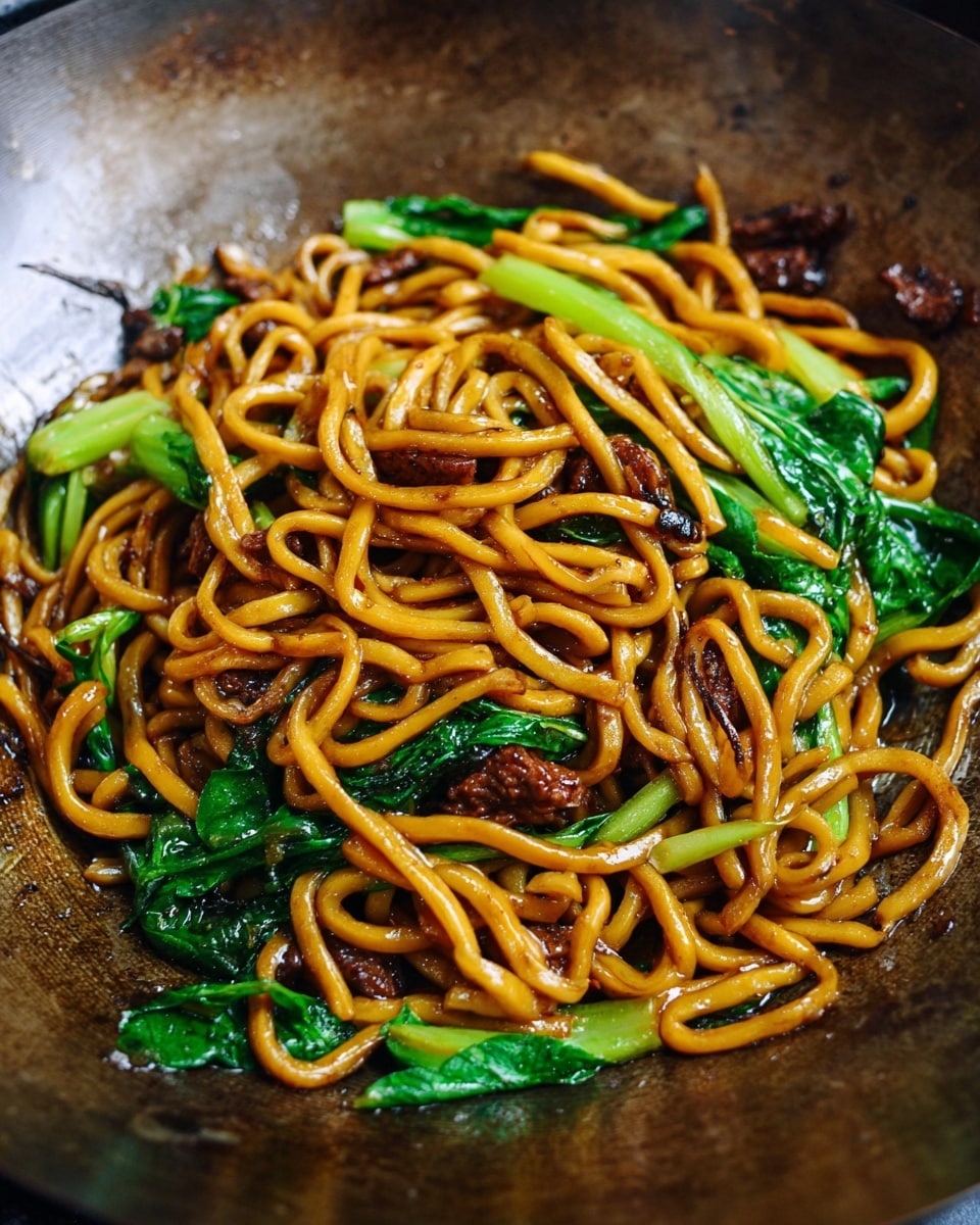 Two white bowls with blue patterns hold cooked thick yellowish-orange noodles mixed with dark brown mushroom pieces and bright green leafy vegetables. The noodles and mushrooms look shiny and coated with sauce, and the green vegetables add fresh color on top and around the noodles. In the background, there is a partially blurred tall bottle with a yellow label and a small white saucer plate filled with dark soy sauce and a wooden spoon, all placed on a white marbled surface. Photo taken with an iphone --ar 4:5 --v 7