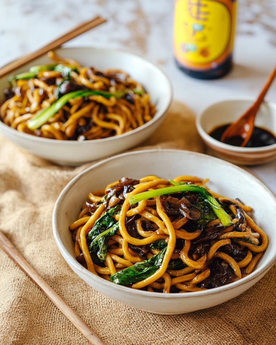 Two white bowls filled with three layers of thick, shiny golden-brown noodles mixed with dark brown pieces of mushrooms and bright green leafy vegetables, placed on a rough tan fabric over a white marbled surface. In the background, a bottle with a yellow label sits next to another white bowl that holds a dark sauce with a wooden spoon inside it. The colors are warm and natural with soft natural light highlighting the textures of the noodles and vegetables. Photo taken with an iphone --ar 4:5 --v 7