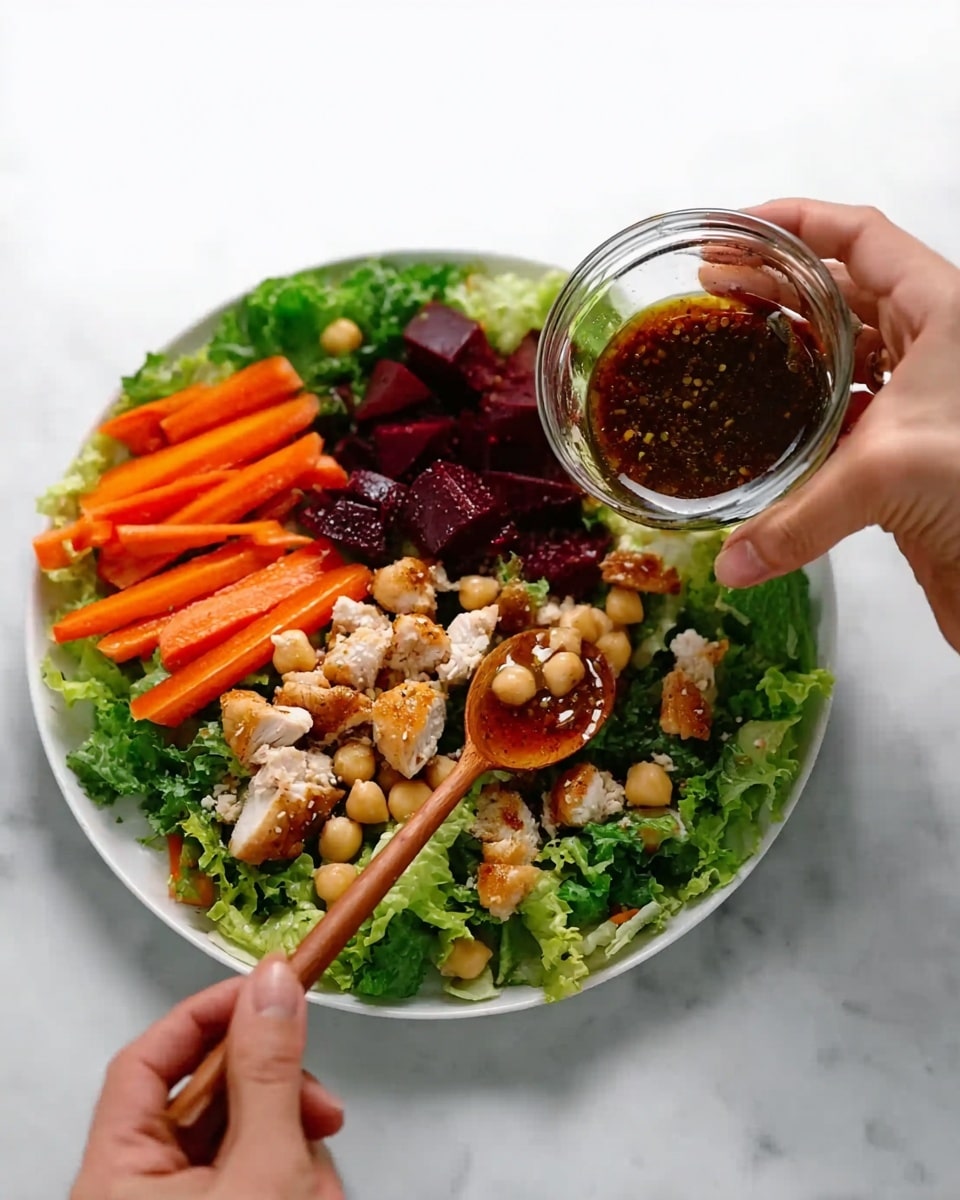 A white plate on a white marbled surface holds a fresh salad with three layers. The base layer is green lettuce leaves spread across the plate. On top, there are bright orange baby carrots placed on one side, while the other side has deep red beet chunks and light beige chickpeas scattered evenly. The top layer features small pieces of cooked light brown chicken arranged across the salad. A woman's hand is holding a small glass bowl containing dark brown dressing, and another woman's hand is using a wooden spoon to drizzle the dressing over the salad. Photo taken with an iphone --ar 4:5 --v 7