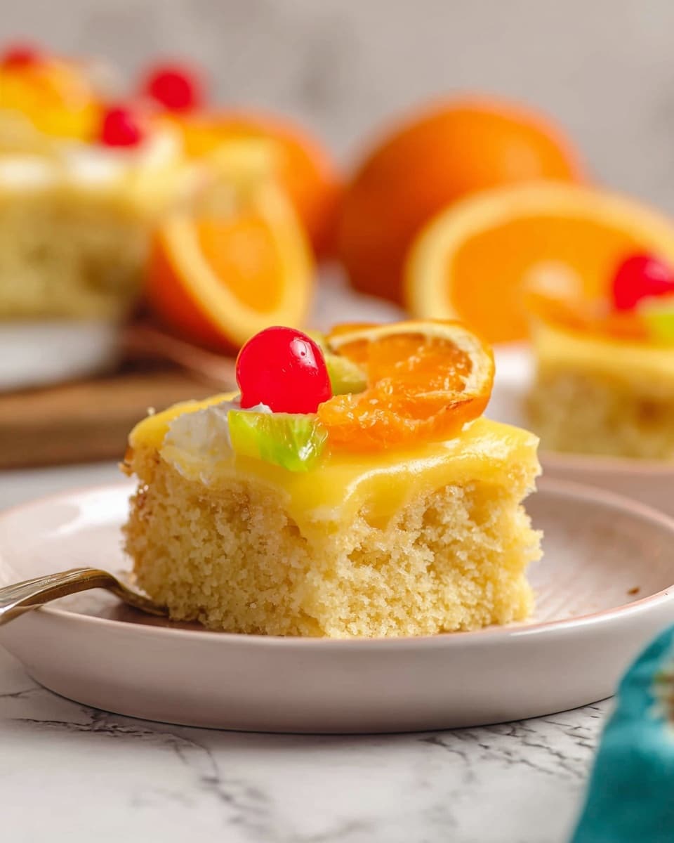 A close-up of a single square slice of yellow, moist cake on a white plate with a white marbled surface. The cake has two layers: the bottom layer is soft and crumbly, the top layer is a thicker, creamy yellow frosting. The slice is topped with colorful fruit pieces—a red cherry in the center, a small green pineapple chunk behind it, and a thin orange slice on the right. In the blurry background, there is a full cake with similar toppings and whole and halved oranges nearby. photo taken with an iphone --ar 4:5 --v 7