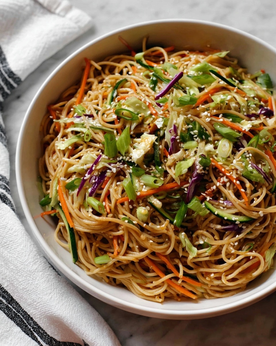 A white bowl filled with a mix of light brown noodles as the main layer, tangled and soft-looking. Mixed in are thin, long strips of green cucumber and bright orange carrots, adding fresh colors. There are also some small pieces of shredded white and purple cabbage. Scattered green onion slices are spread on top, giving a fresh touch. Tiny white sesame seeds are sprinkled all over. The bowl sits on a white marbled surface, next to a white cloth with black stripes. Photo taken with an iphone --ar 4:5 --v 7