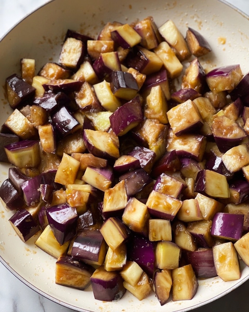 The image shows a close-up of a white pan filled with a thick vegetable stew. The stew has large chunks of purple eggplants, bright red tomatoes, green peas, and dark green leafy vegetables mixed in a rich, chunky orange-red tomato sauce. A light blue spatula with a wooden handle is scooping some of the stew, highlighting the vibrant colors and varied textures of the soft, cooked vegetables. The background features a white marbled surface. photo taken with an iphone --ar 4:5 --v 7