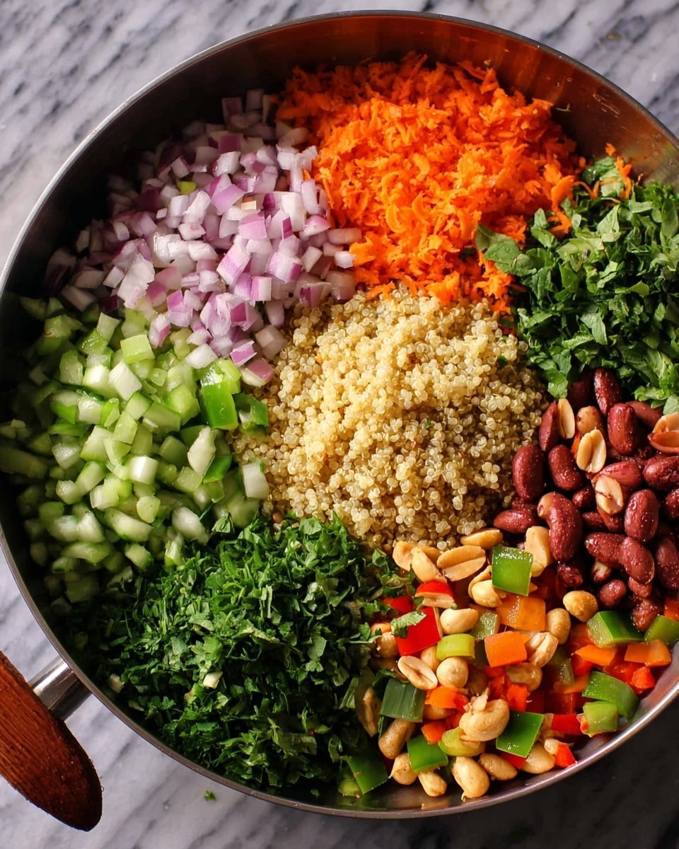 A clear glass bowl filled with a colorful quinoa salad sits on a white marbled surface. The salad has three visible layers: the bottom layer is light beige quinoa mixed with green herbs, the middle layer shows bright dark red beans and orange carrot pieces, and the top layer is a mix of fresh green herbs, chopped cucumber pieces, small red bell pepper bits, and white onion pieces that add texture and brightness. In the blurred background, there is a red pan with more of the salad inside. A golden spoon is partly visible on the right side. The photo taken with an iphone --ar 4:5 --v 7