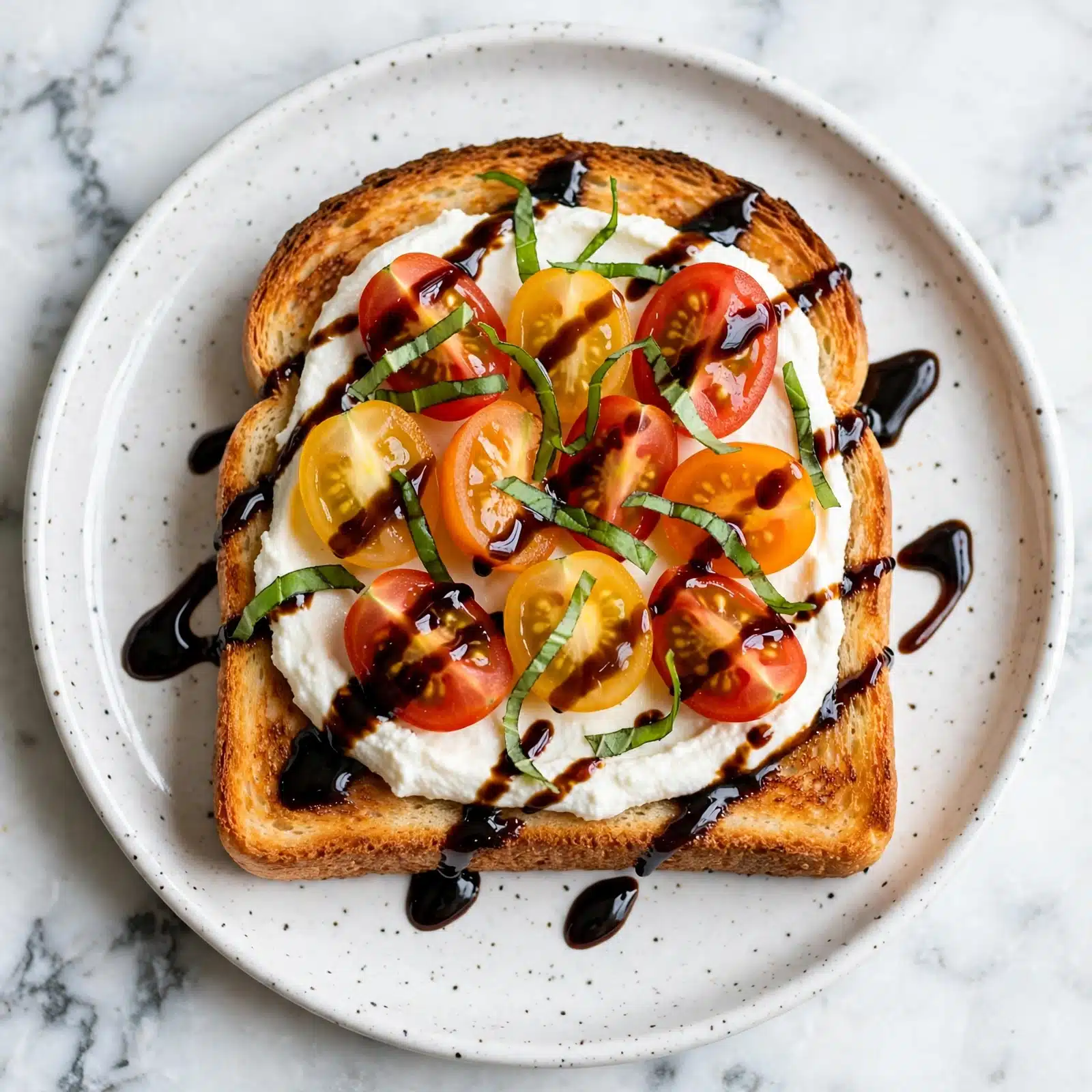 Bruschetta-ish Cottage Cheese Toast Recipe 5 Two pieces of toasted bread sit on a white plate with brown speckles over a white marbled surface. Each toast is covered with a layer of white cottage cheese, topped with a mix of halved red, yellow, and dark cherry tomatoes, and thin green basil strips. The tomatoes and basil are lightly drizzled with a dark balsamic glaze. The toasts have a golden-brown edge and slightly crisp texture. Sunlight highlights the bright colors and fresh textures. photo taken with an iphone --ar 4:5 --v 7