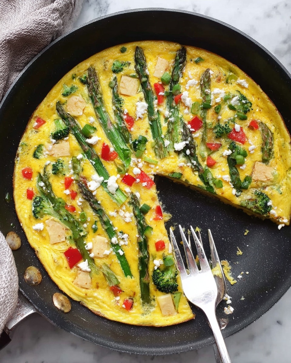 A round egg dish cooked in a black pan with a white handle sits on a white marbled surface with a dark cloth nearby. The top layer is bright yellow with a soft, slightly bumpy texture. There are pieces of green asparagus arranged like spokes from the center to the edges. Scattered across the dish are small red tomato chunks, green leafy herbs, and light pink square pieces of ham. The overall composition shows a colorful, fresh vegetable and ham egg mixture. Photo taken with an iphone --ar 4:5 --v 7